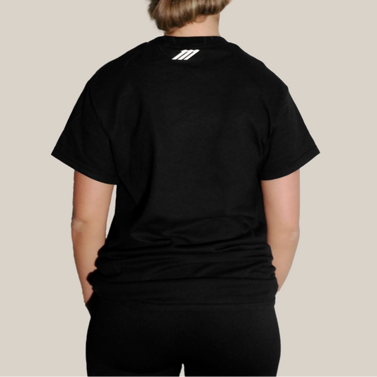 Person wearing a Motion black t-shirt with a Motion logo on the back against a beige background