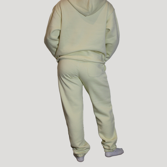 Light yellow hoodie and pants set on a plain background