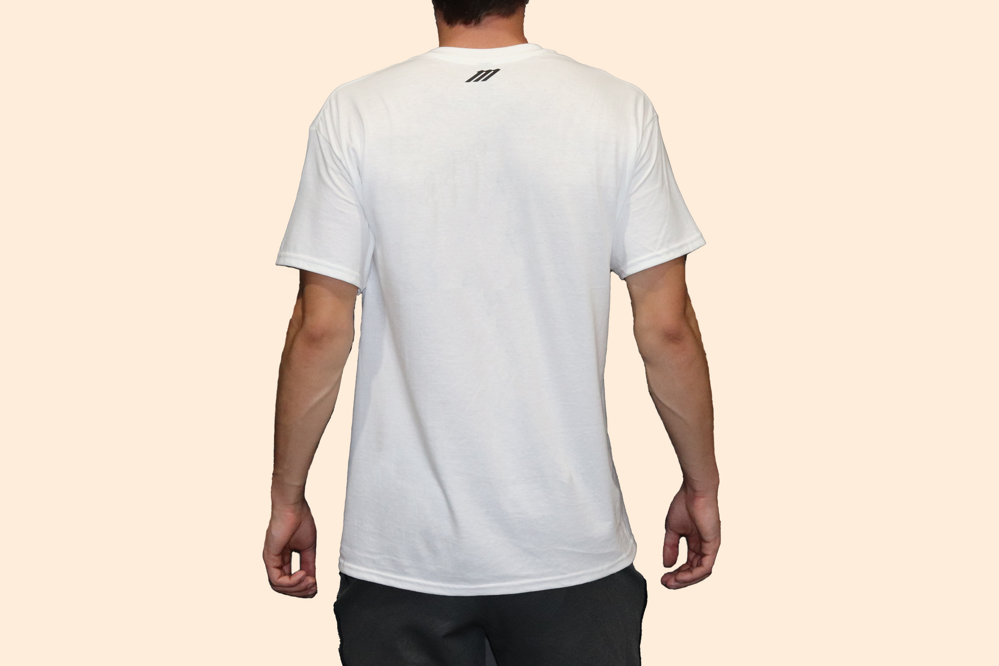 Person wearing a white t-shirt with a brand logo on the back against a beige background