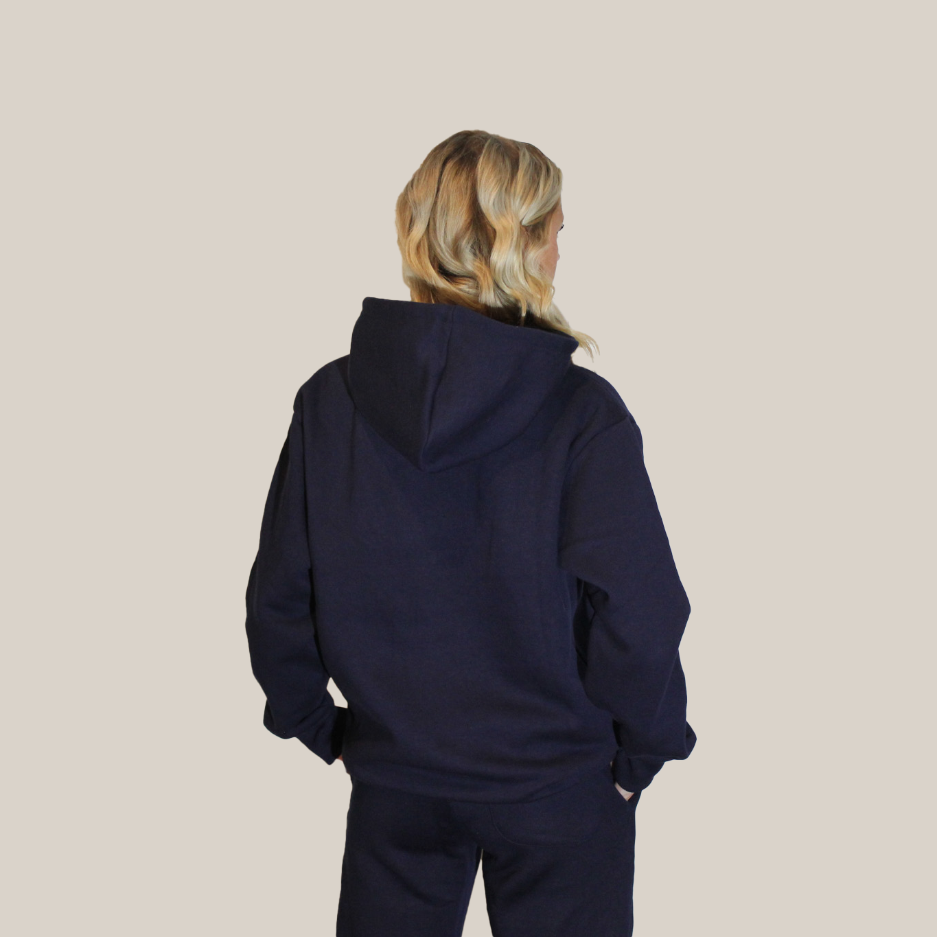 Person wearing a navy blue Motion Clothes hoodie and pants on a beige background