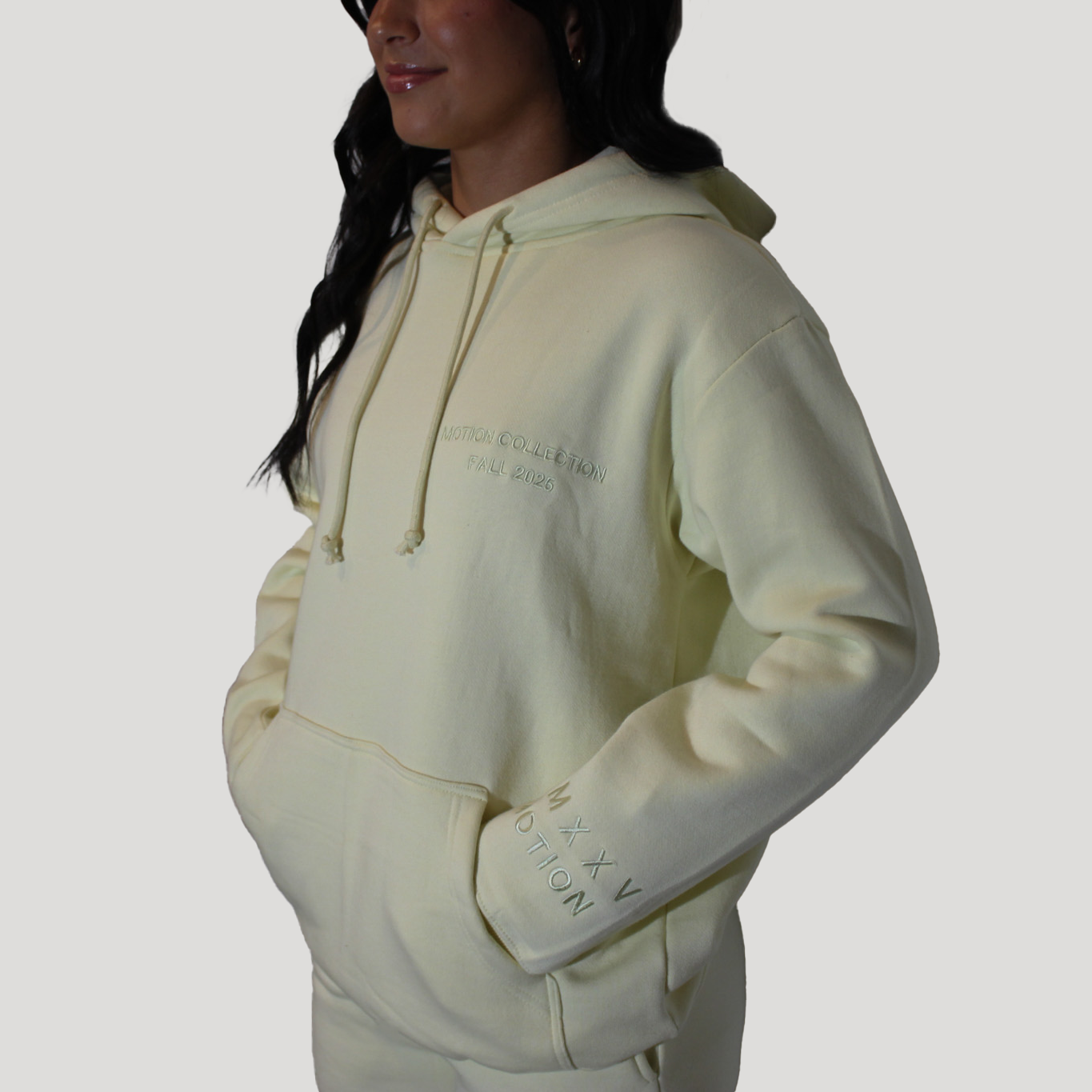 Person wearing a light-colored Motion Signature hoodie on a plain background
