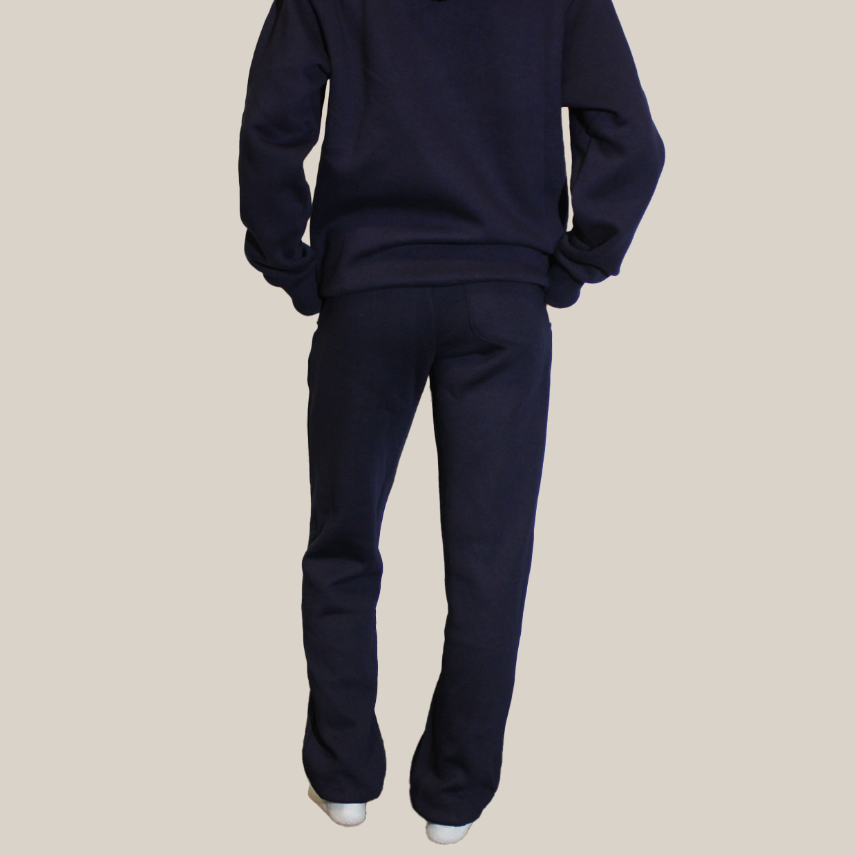 Person wearing a navy blue Motion tracksuit on a beige background