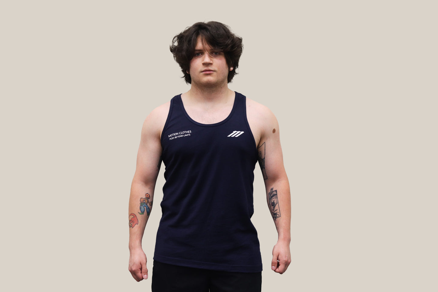 Model wearing a navy tank top with a logo on a beige background