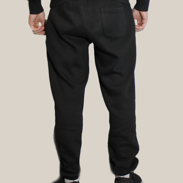 Person wearing a Motion signature black hoodie and signature motion black pants on a beige background