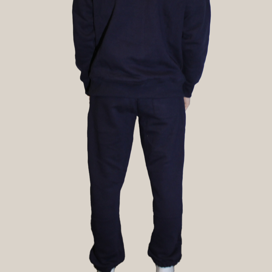 Person wearing a navy blue Motion tracksuit on a beige background