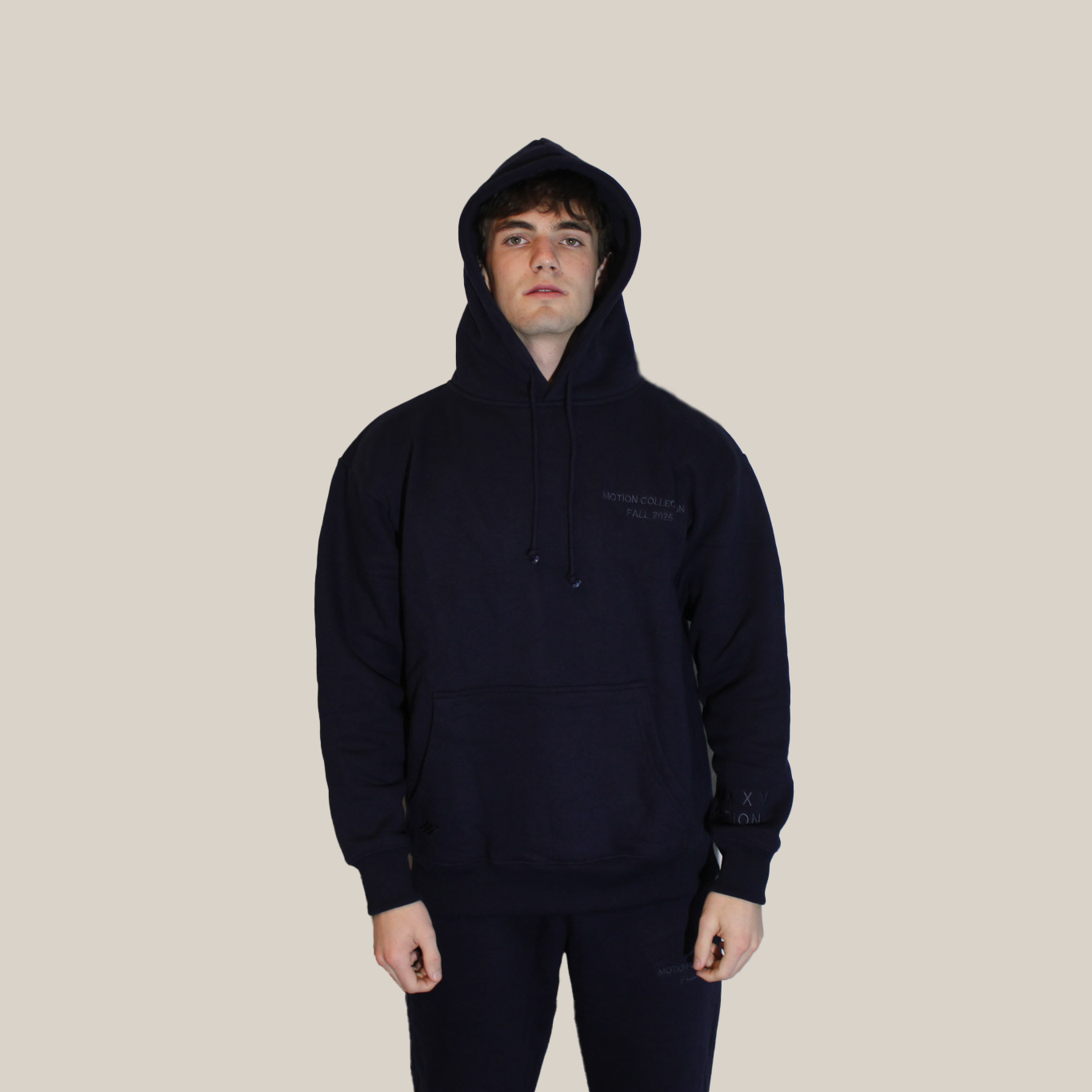 Person wearing a black hoodie on a beige background with Motion logo on hoodie pocket