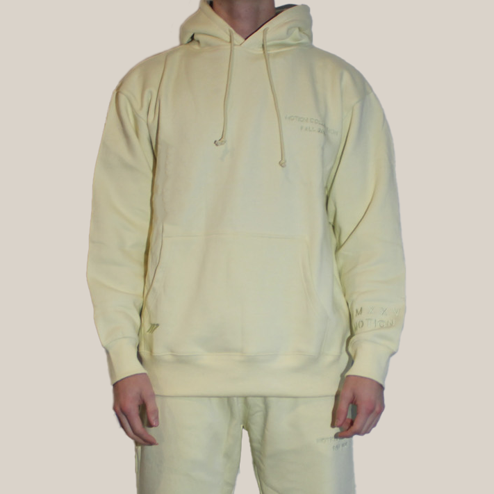 Person wearing a light yellow Motion hoodie on a beige background