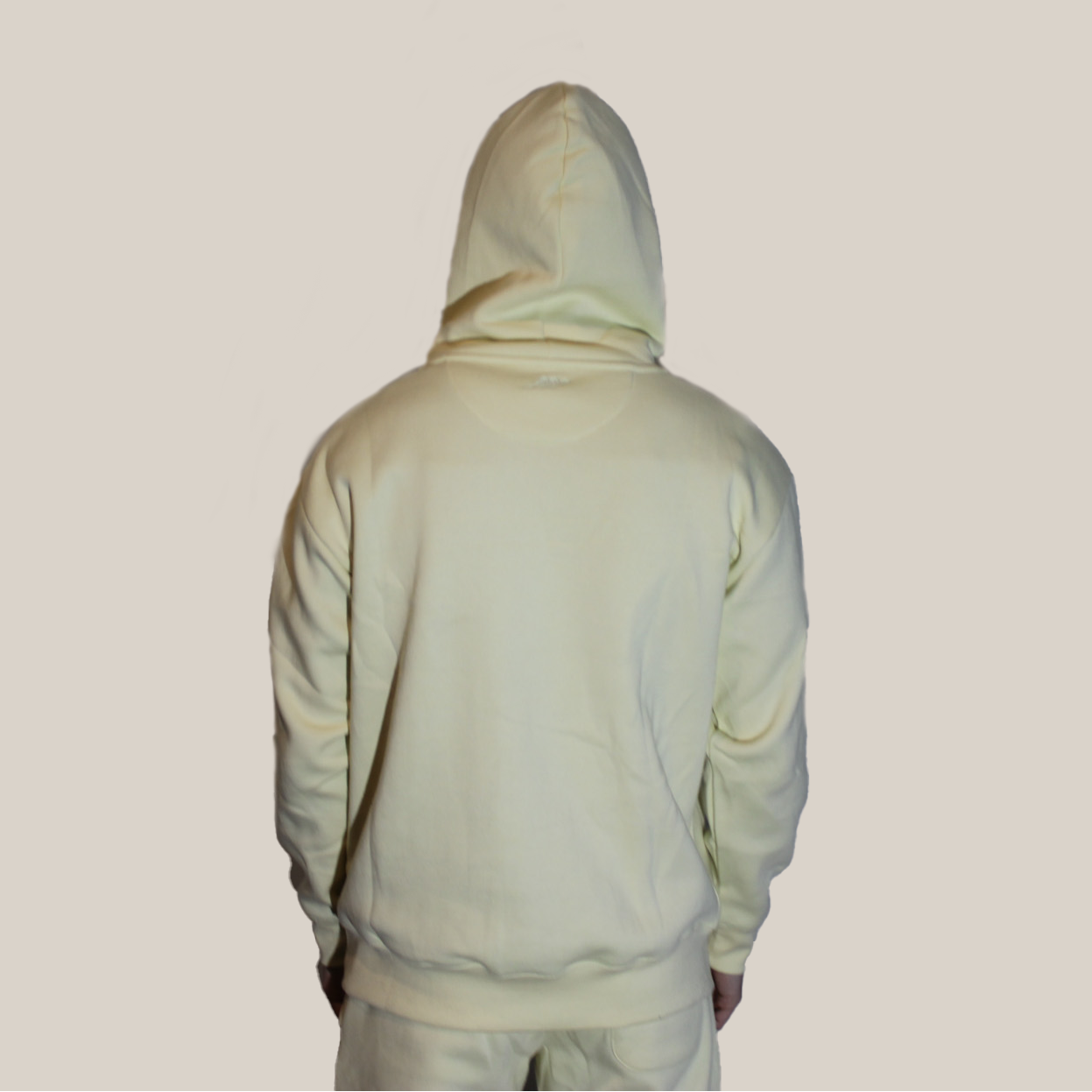Person wearing a light yellow Motion hoodie and pants on a beige background